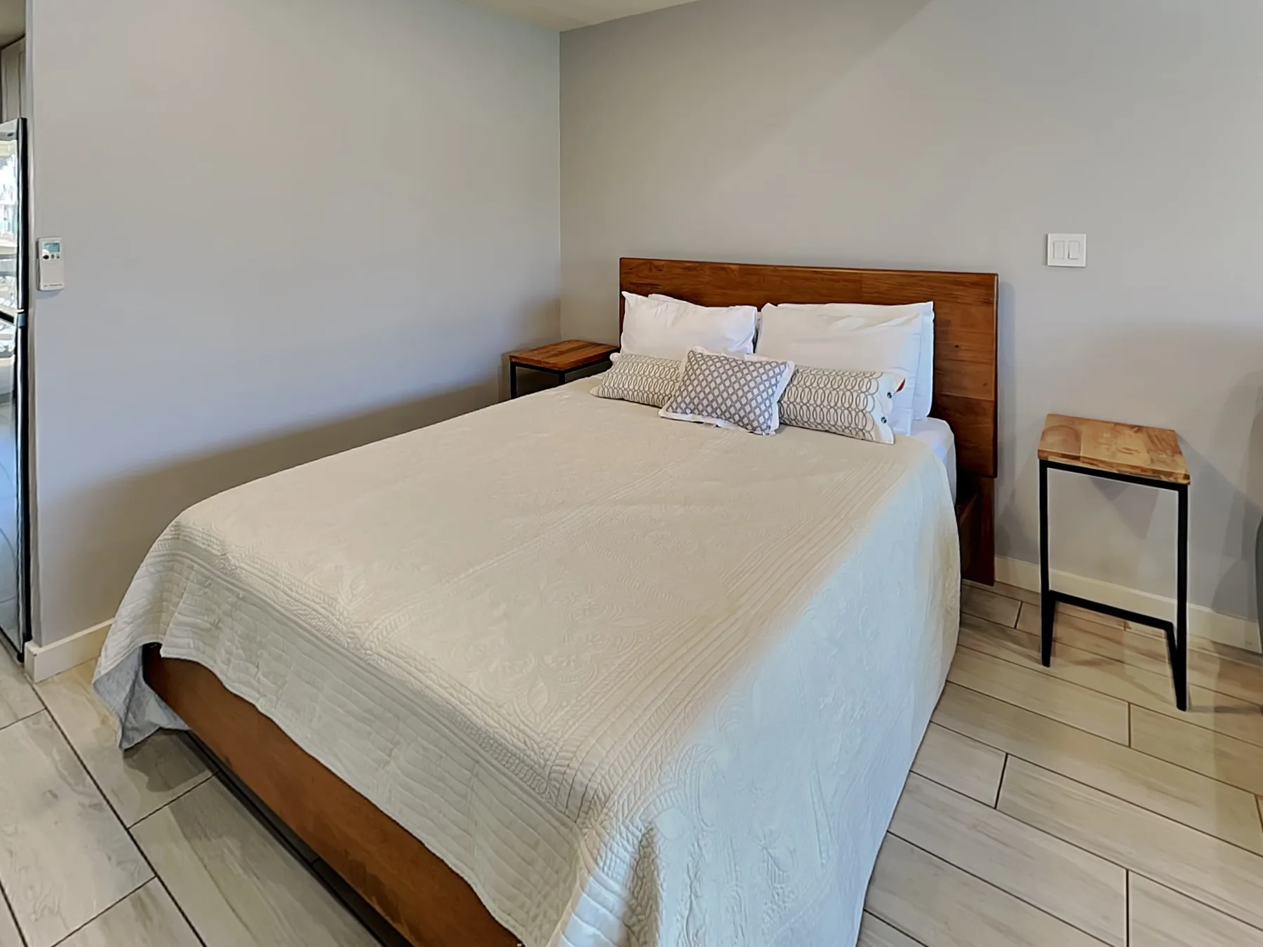 A bedroom with a neatly made bed and wooden headboard.