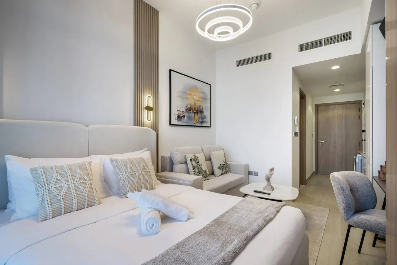 Un dormitorio con una cama grande, asientos junto a la pared y arte enmarcado.