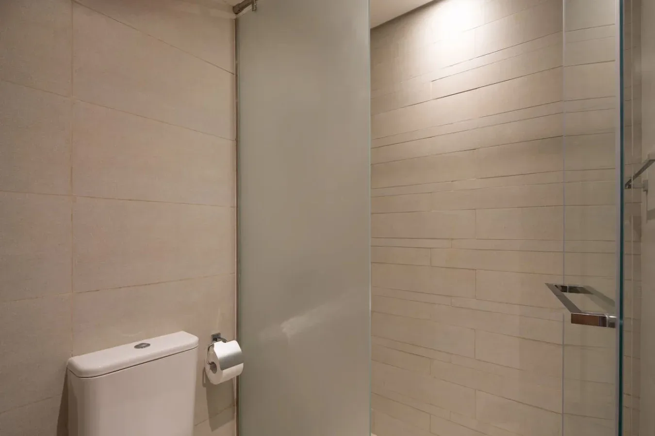 Un baño con un inodoro y una zona de ducha con azulejos.