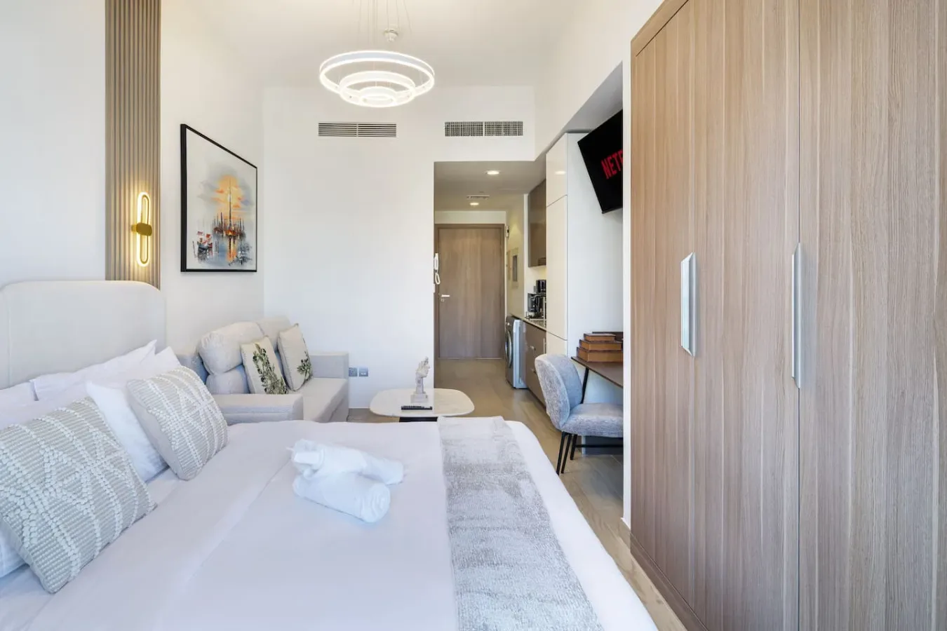 Un dormitorio luminoso con una cama bien tendida y una zona de estar.