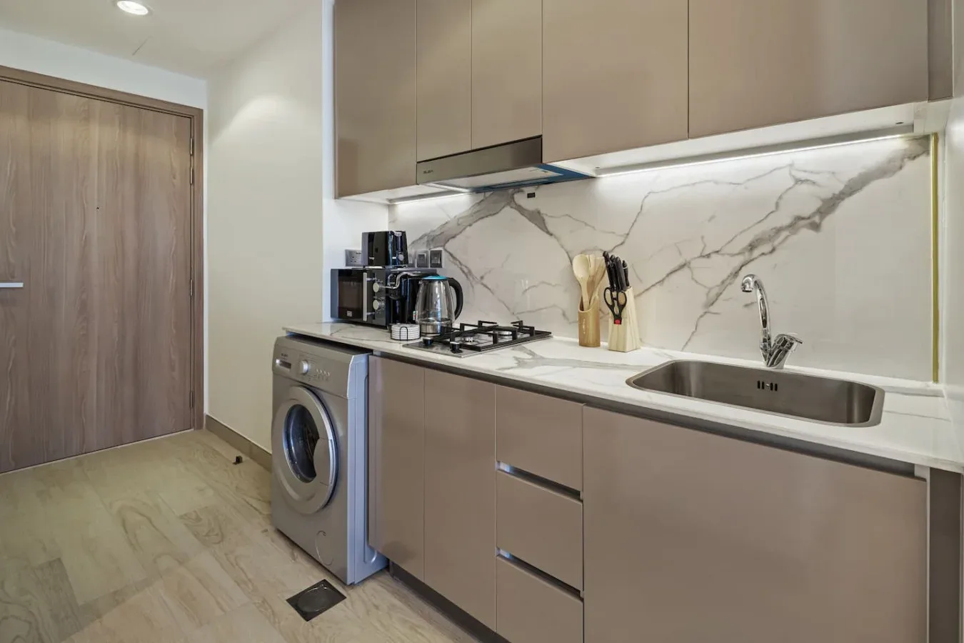 Una cocina moderna con placa de cocina, fregadero y lavadora.