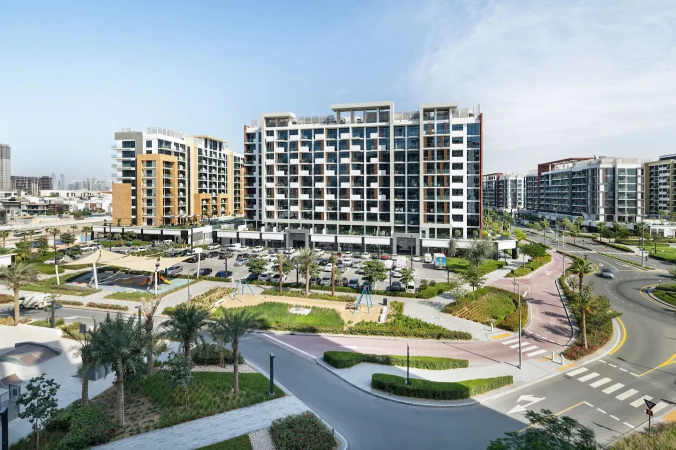 Edificios de apartamentos modernos dan a jardines y una carretera curva.
