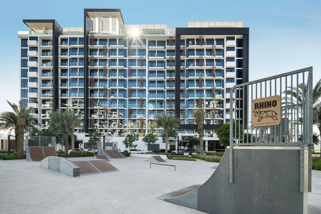 Un edificio de apartamentos moderno da a un parque de skate al aire libre.