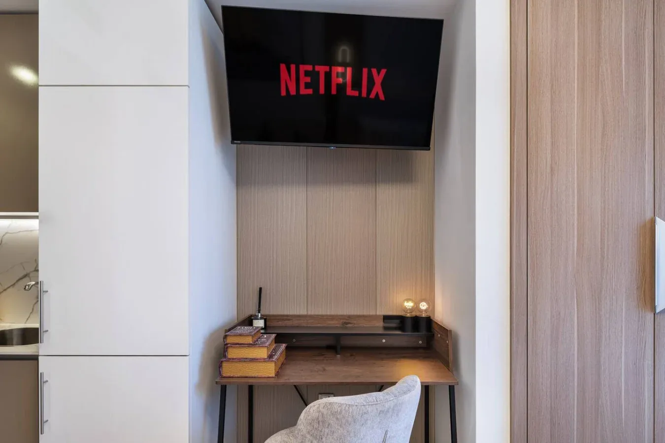 Un escritorio compacto está bajo un televisor montado en la pared.