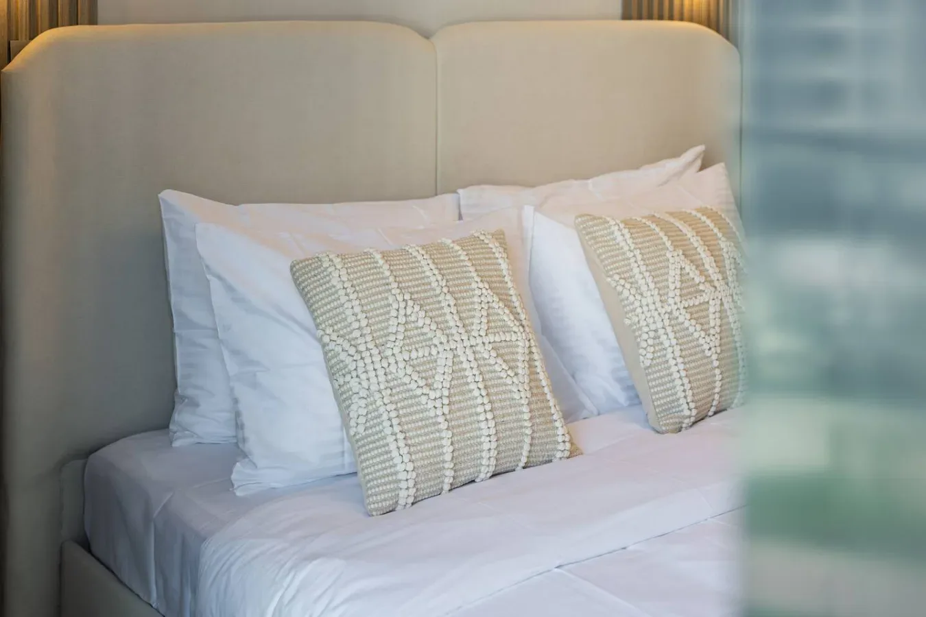 Una cama con ropa de cama blanca y cojines decorativos.