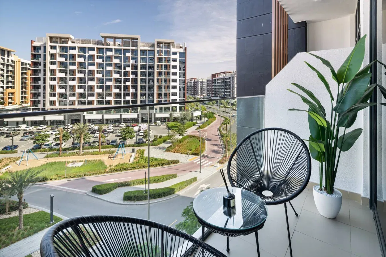 Una zona de estar en el balcón da a senderos ajardinados y edificios de apartamentos.