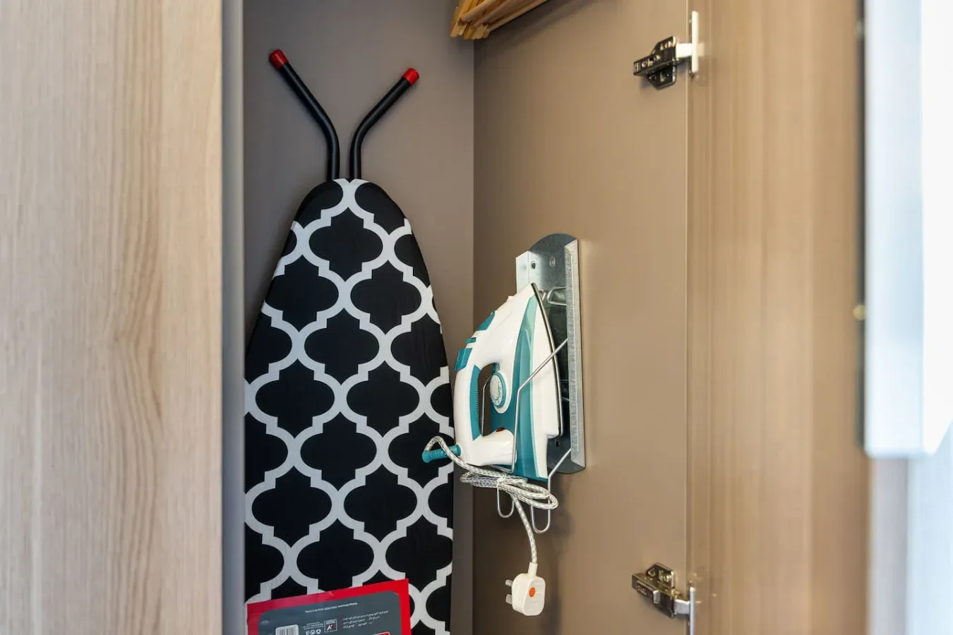 Una zona de planchado compacta tiene una tabla estampada y una plancha guardada en un armario.