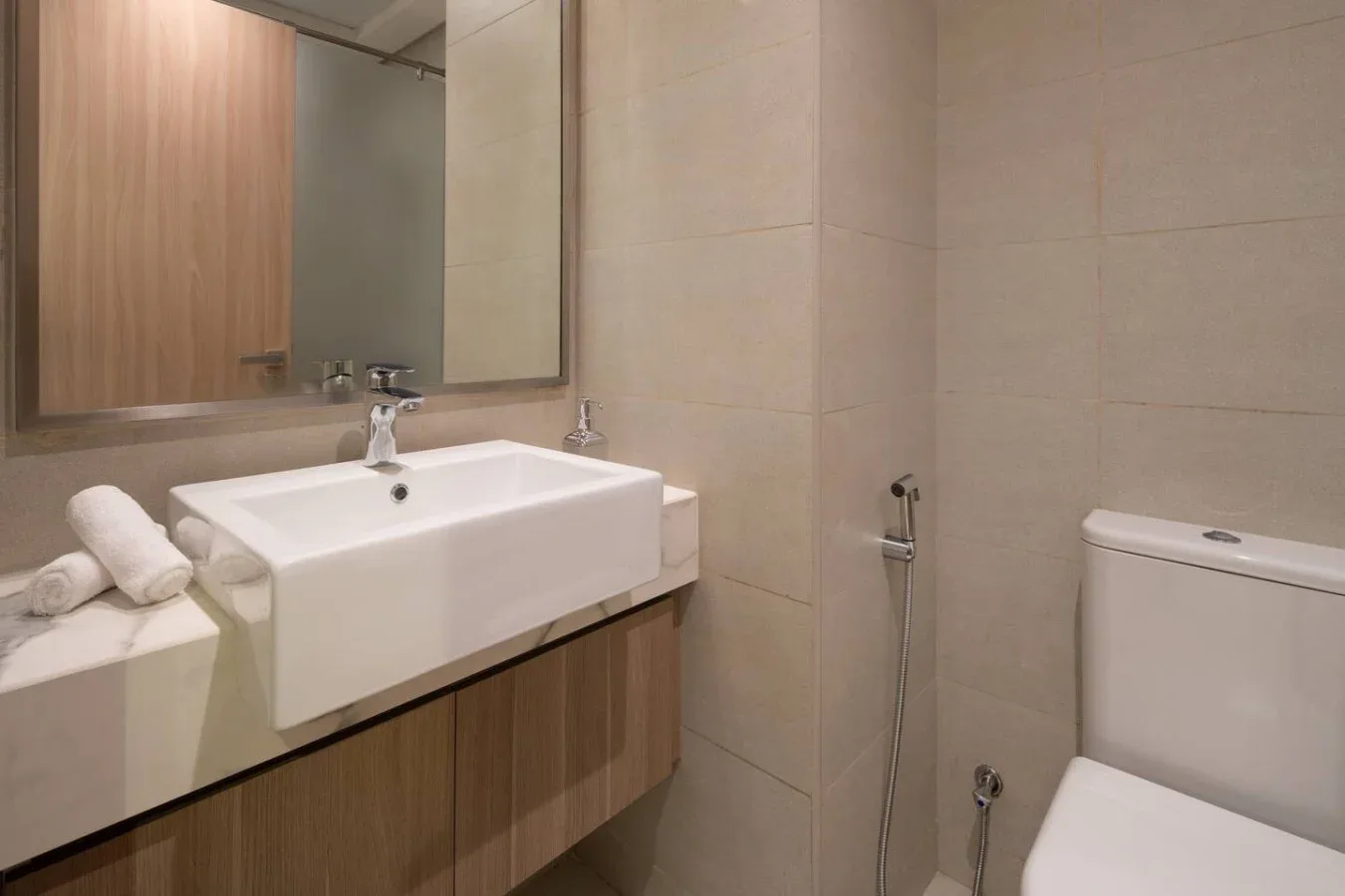 Un baño con un lavabo blanco amplio, un espejo y un inodoro.