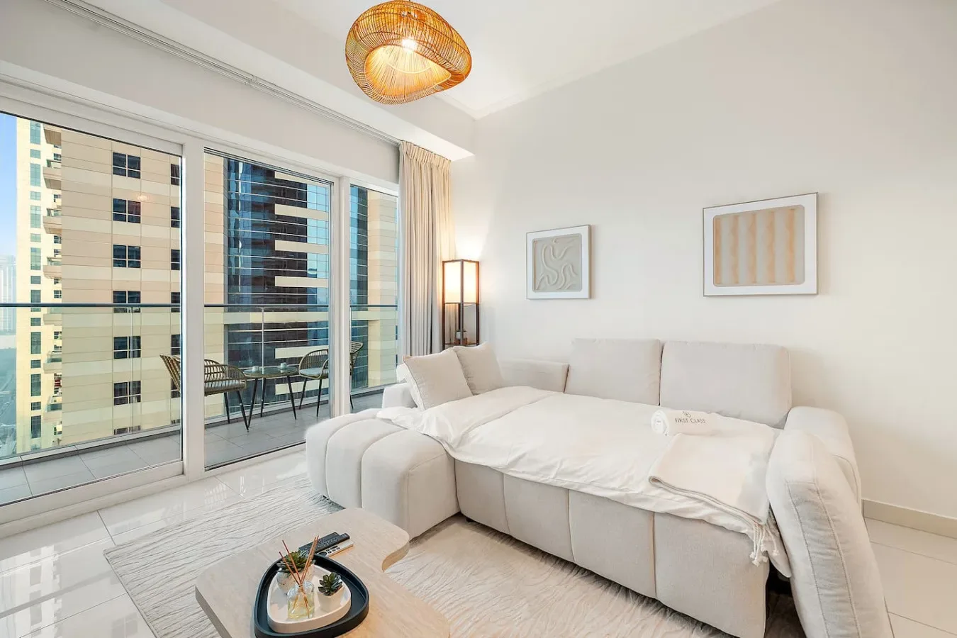 Una sala luminosa con un sofá seccional claro junto a ventanales de piso a techo.