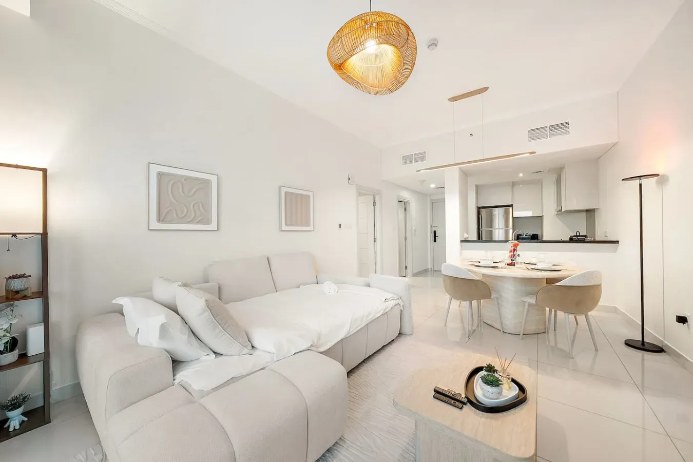 Una sala luminosa con asientos claros y una cocina abierta.