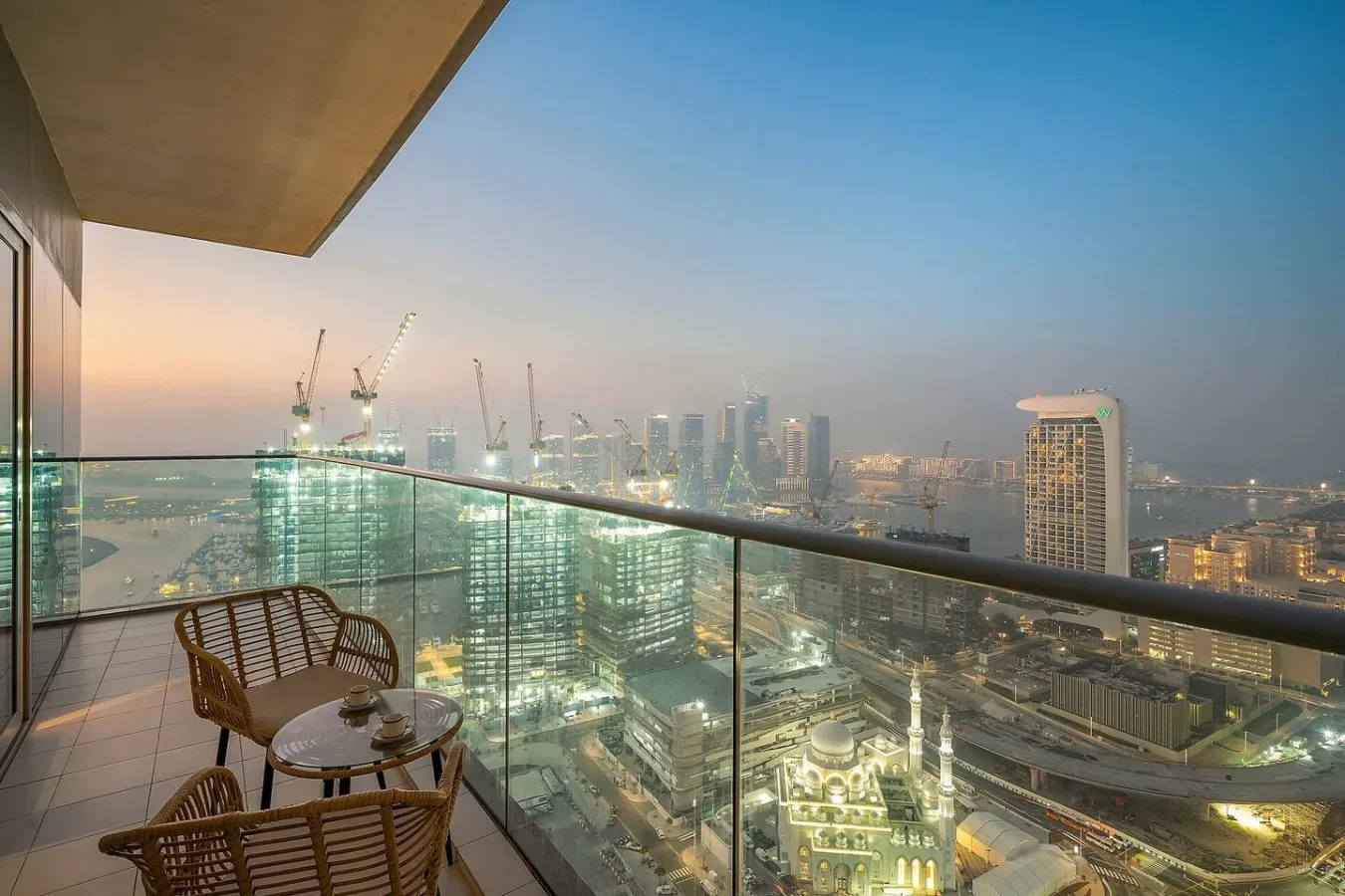 Un balcón ofrece vistas de un horizonte urbano iluminado al anochecer.