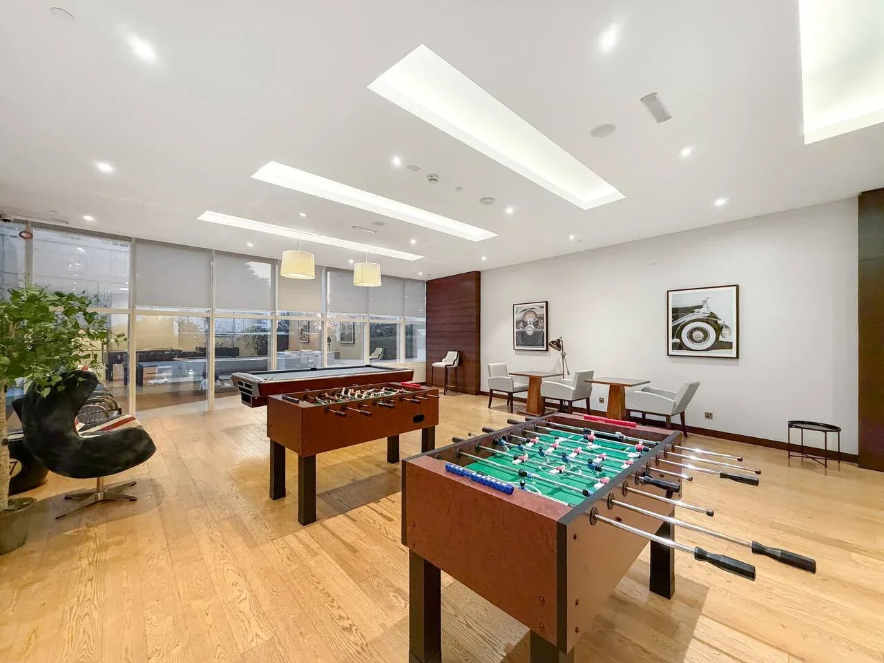 Una sala de juegos con mesas de futbolín, asientos y grandes ventanales.