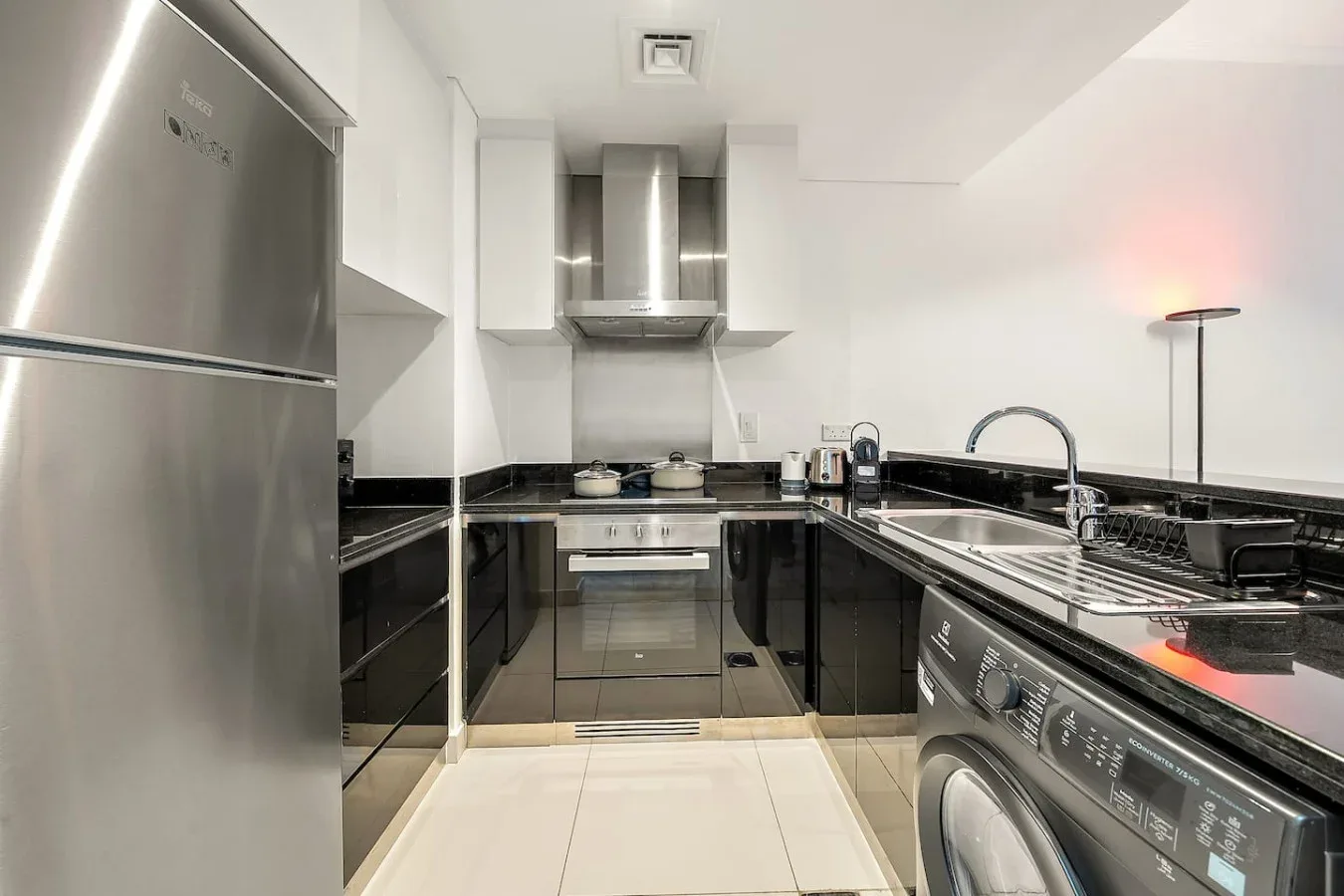 Una cocina moderna con gabinetes oscuros, un refrigerador de acero inoxidable y un fregadero.