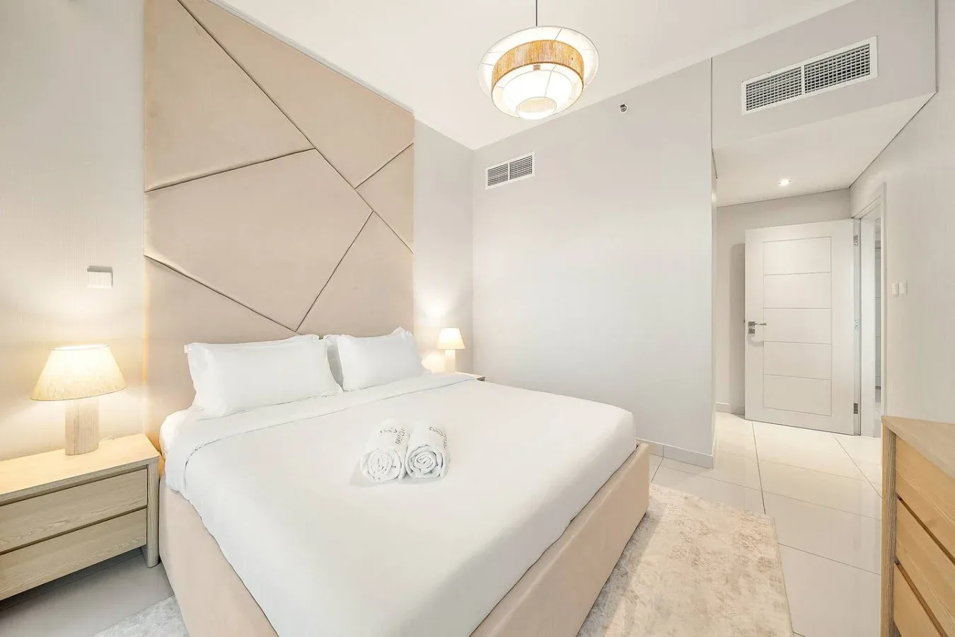 Un dormitorio luminoso con una cama bien hecha y lámparas de noche.
