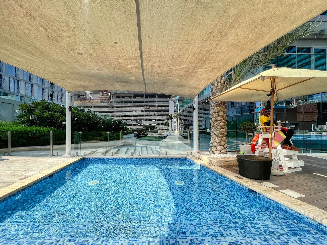 Una piscina al aire libre está bajo toldos junto a edificios modernos.