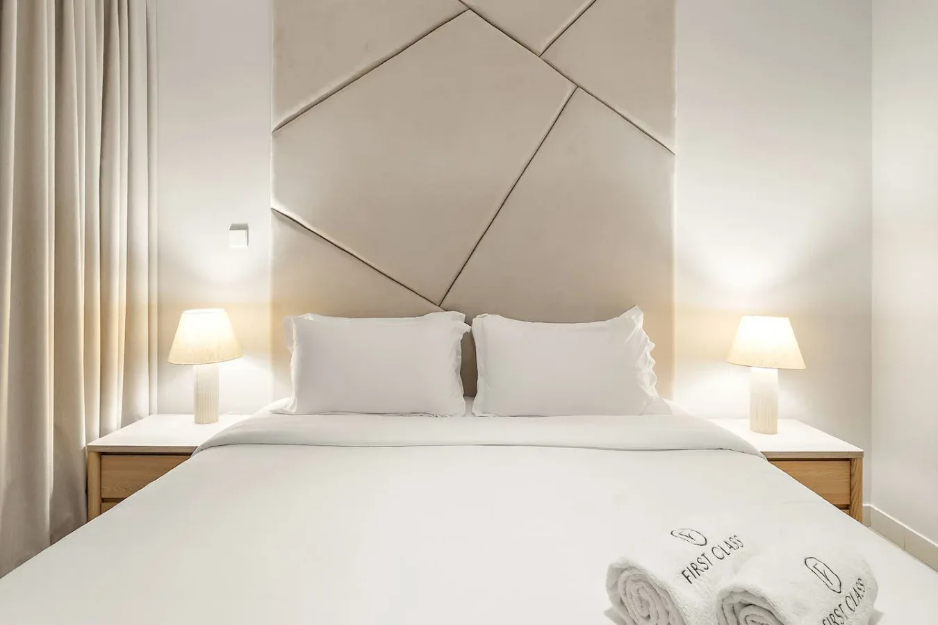 Un dormitorio con una cama bien tendida y lámparas a ambos lados.