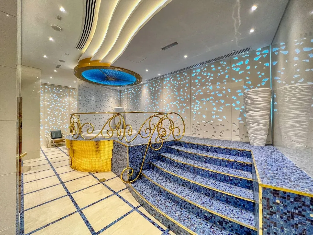 Un interior decorativo de azulejos con escalones curvos y barandales dorados ornamentados.
