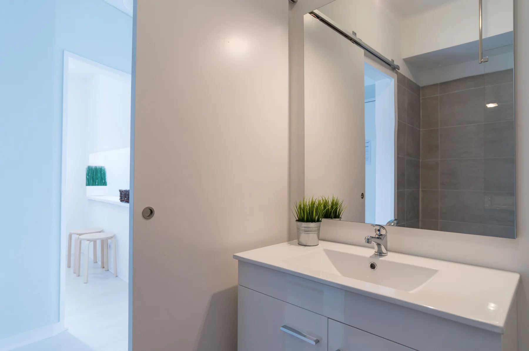 A bathroom vanity with a sink and mirror beside an open doorway.