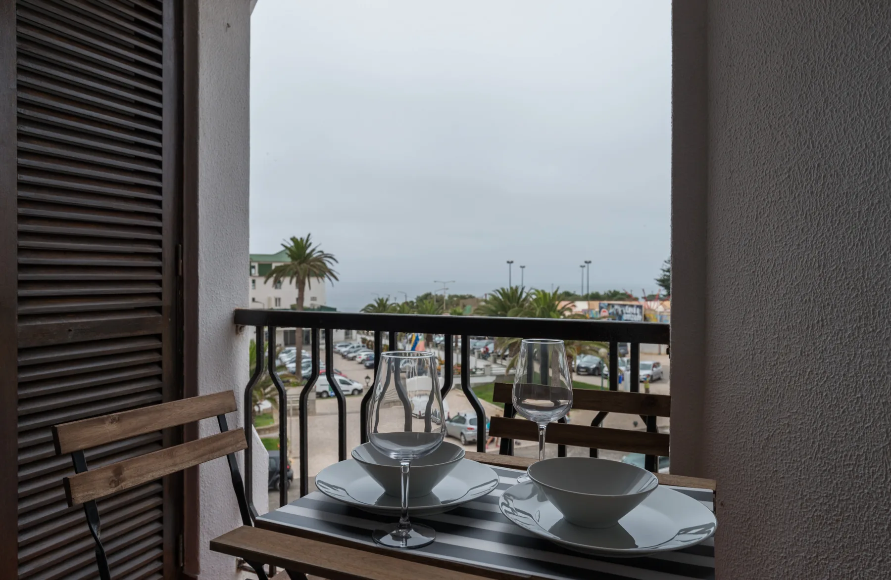 A small balcony dining area overlooks palm trees and nearby buildings.