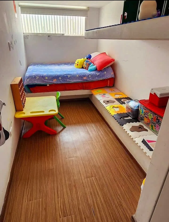 A compact bedroom with a bed, colorful cushions, and a small play table.