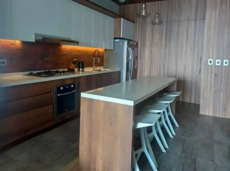 A modern kitchen with a long island and several seats.