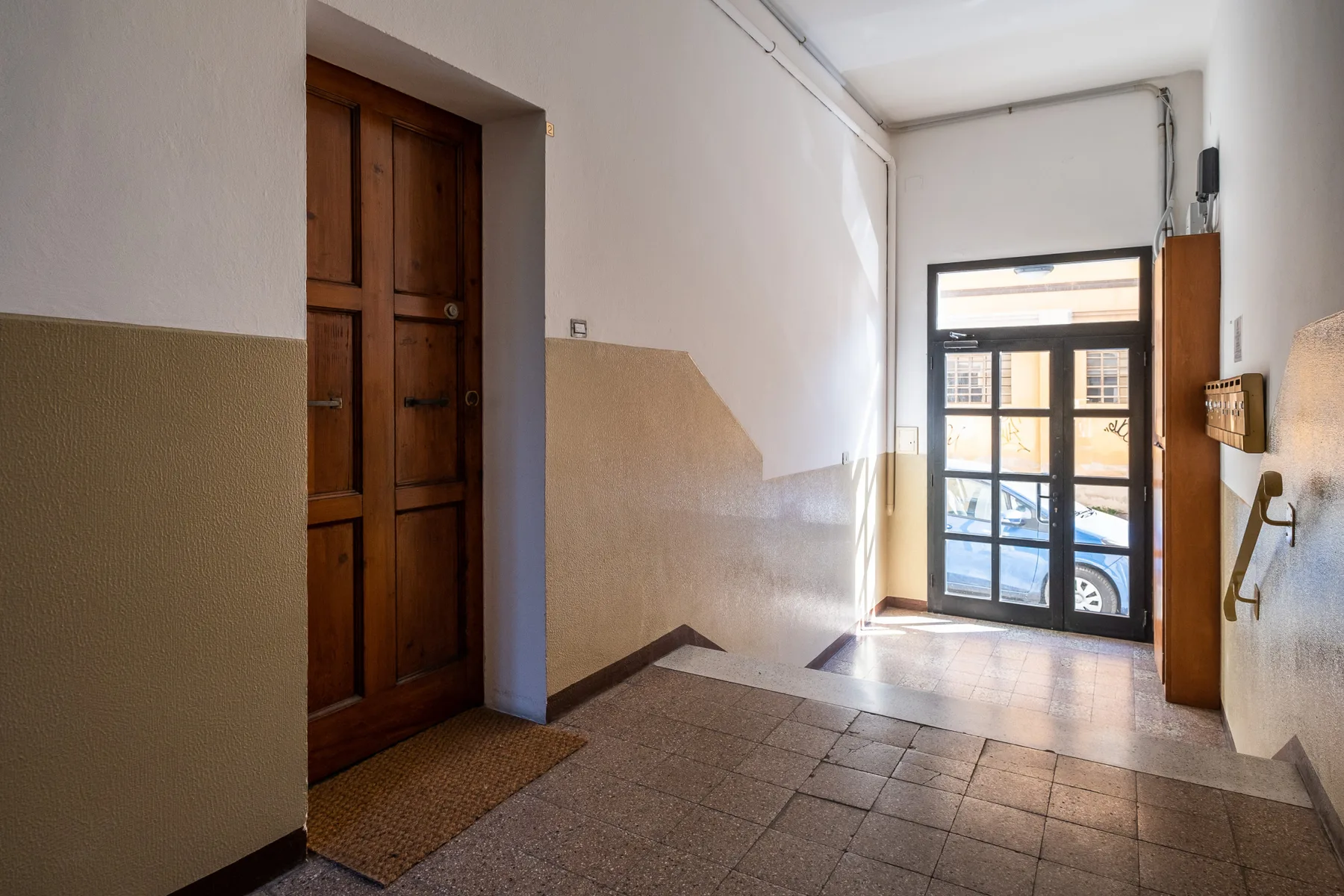 Un vestíbulo de entrada con una puerta de madera y una entrada de vidrio.