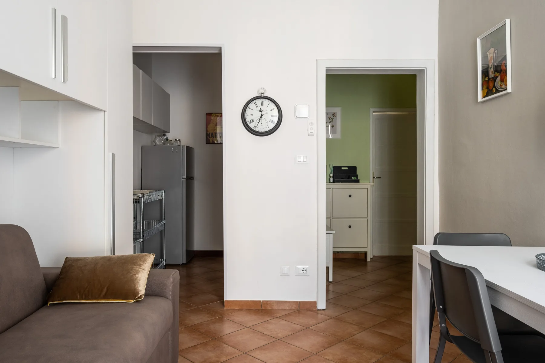 A living and dining area with a sofa, table, and open doorways.