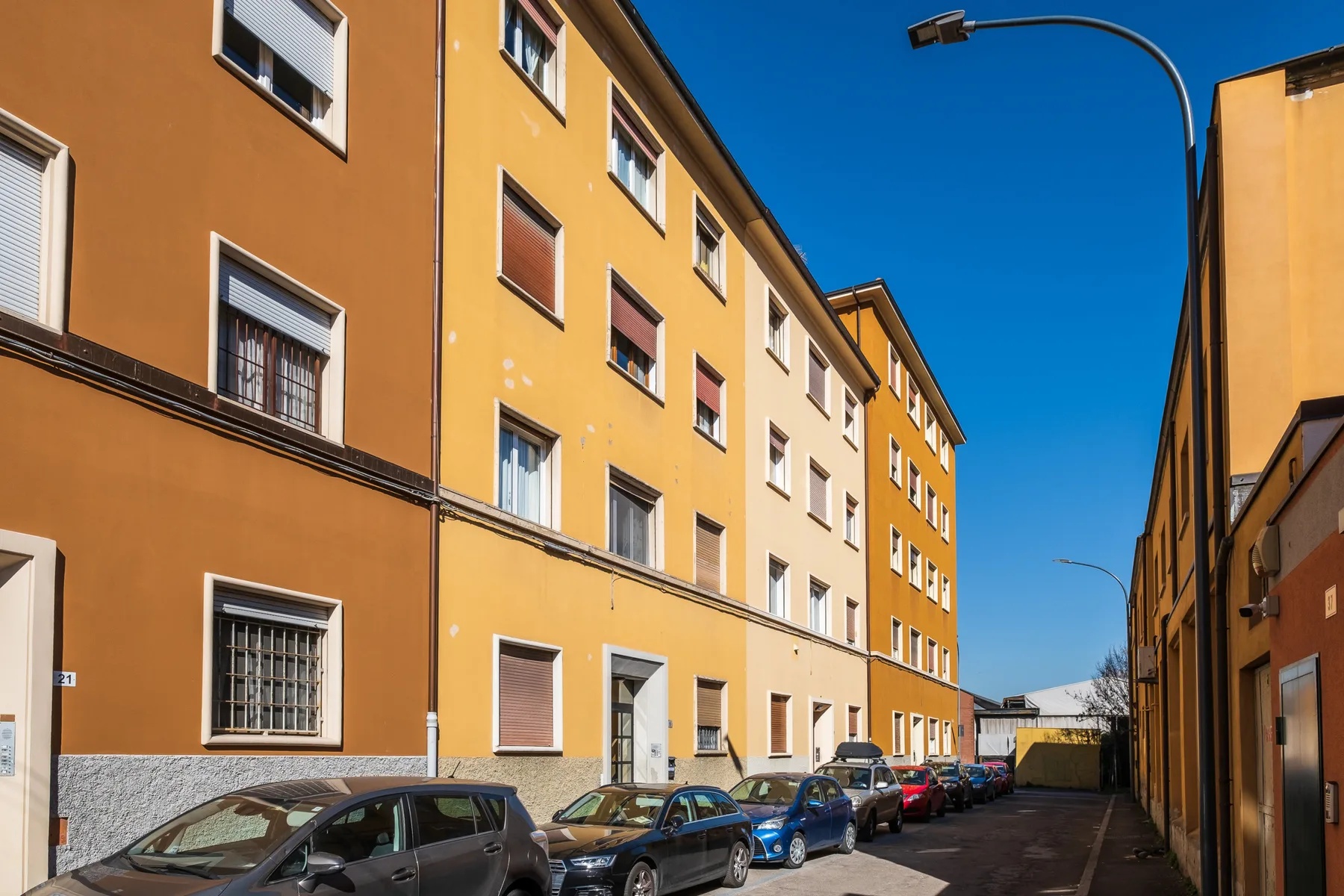 Una calle estrecha entre edificios de apartamentos, con coches estacionados junto a la acera.