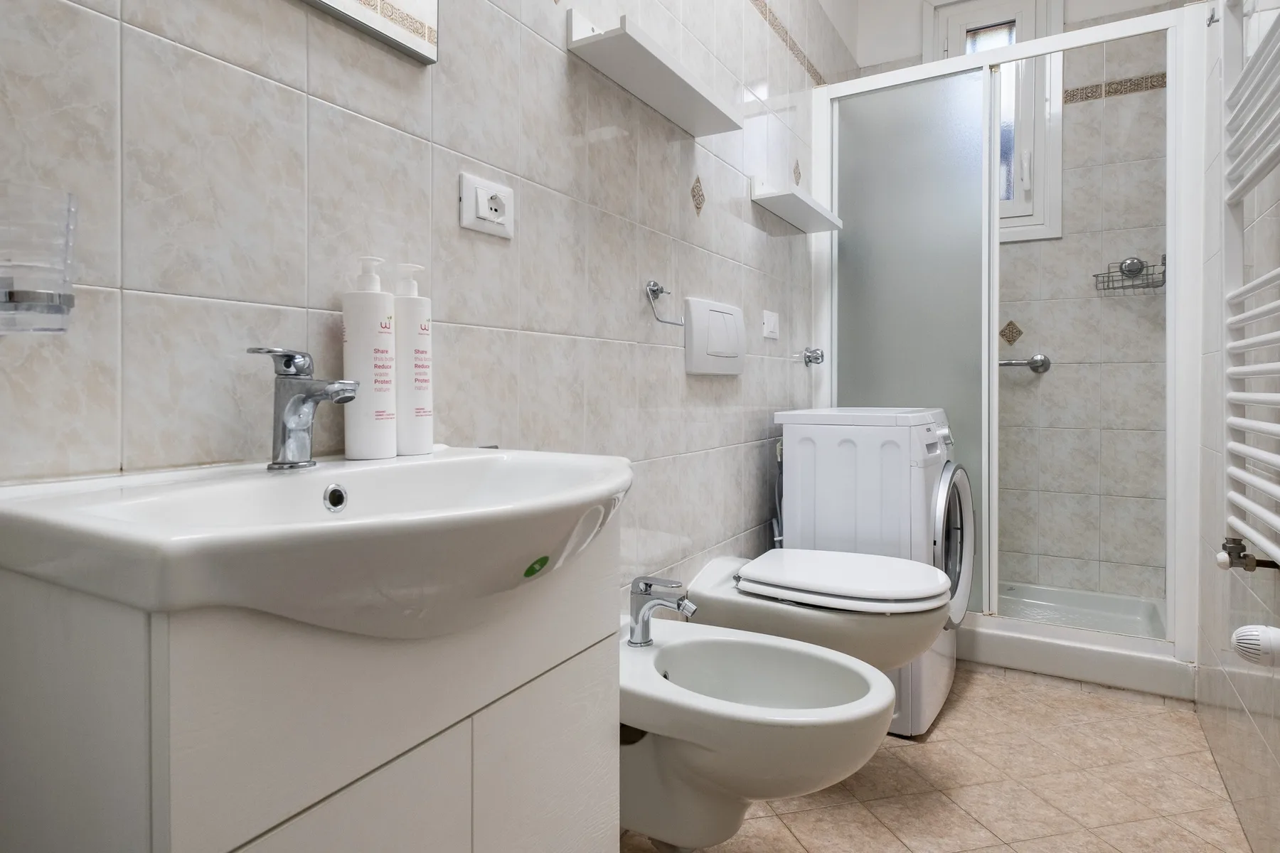 Un baño alicatado con lavabo, inodoro, bidé y ducha.