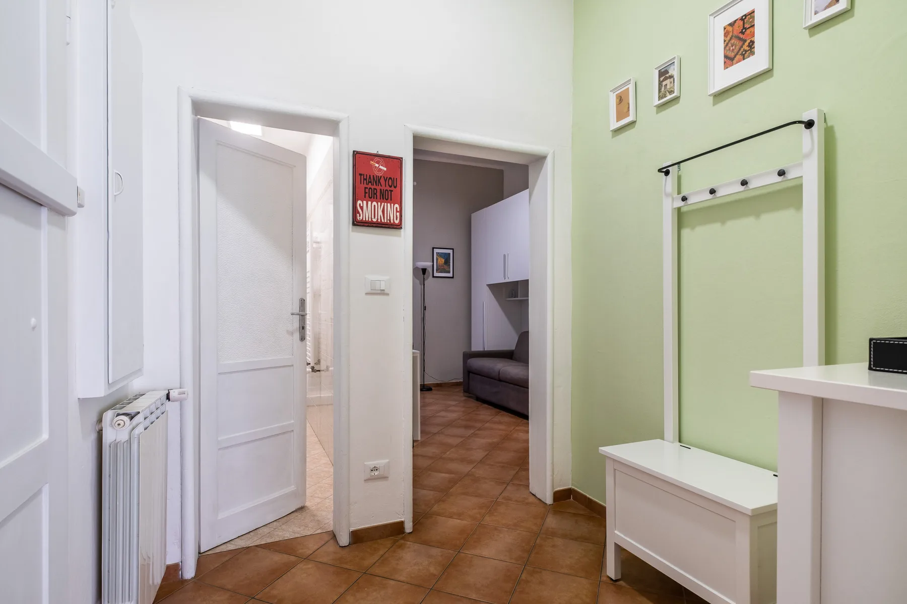 Un pasillo luminoso con puertas abiertas y un perchero de pared.