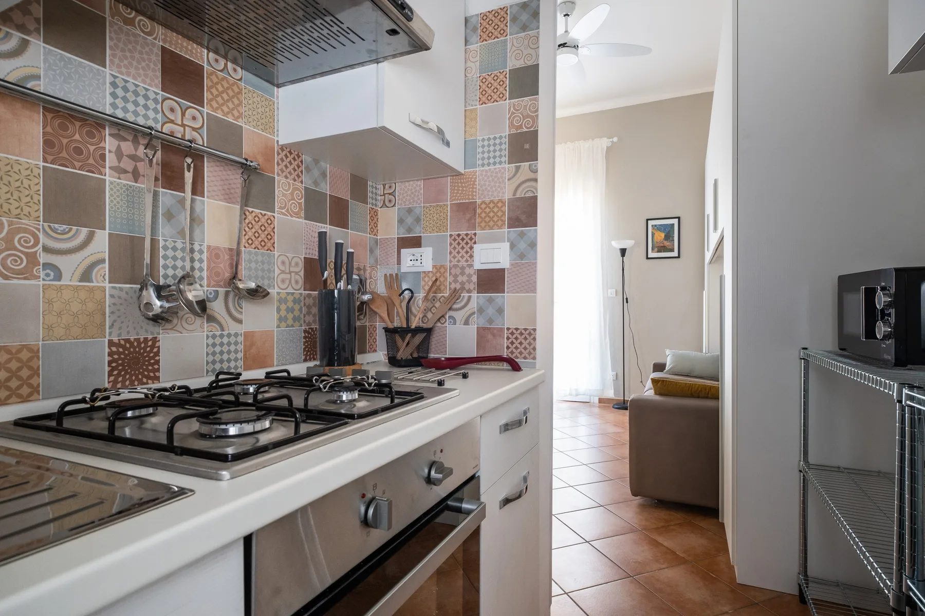 A kitchen with a gas cooktop opens into a living area.