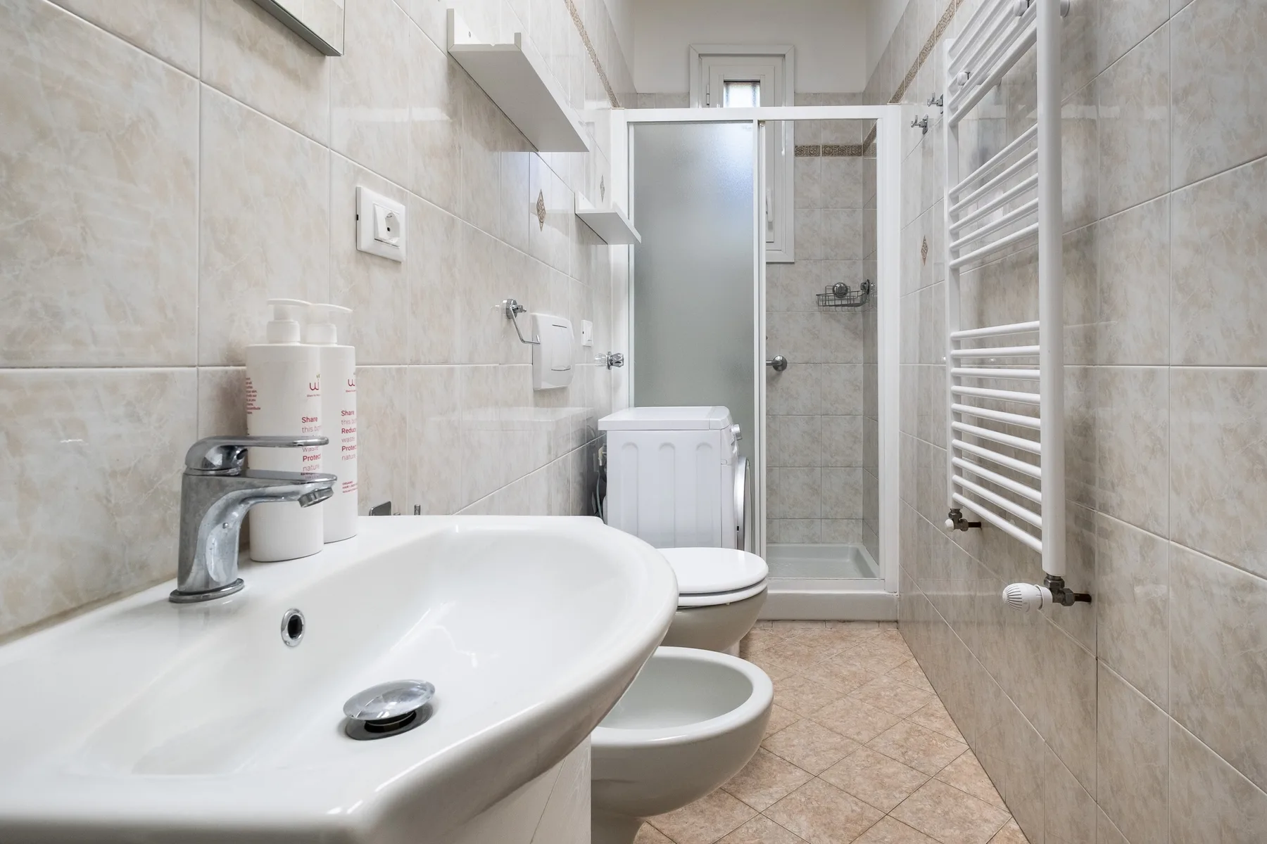 Un baño alicatado con lavabo, inodoro y ducha de vidrio.