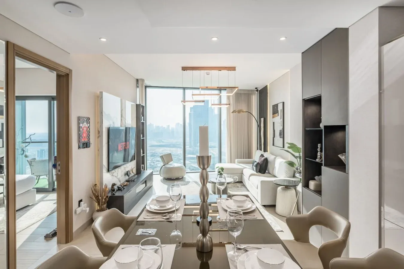 Una luminosa sala de estar y comedor cuenta con una mesa, asientos y grandes ventanales.