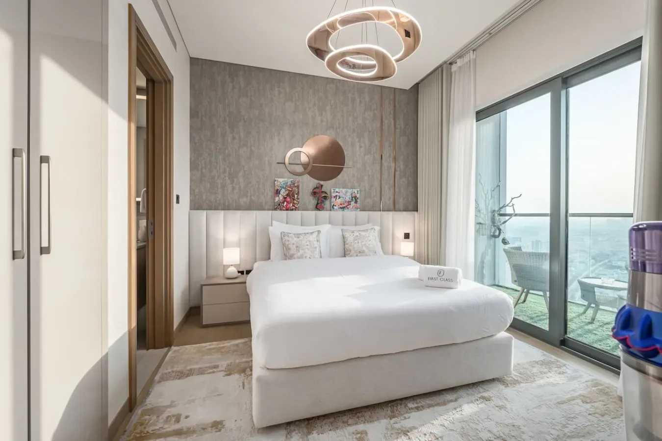 Un dormitorio luminoso con una cama blanca frente a puertas de vidrio de piso a techo.