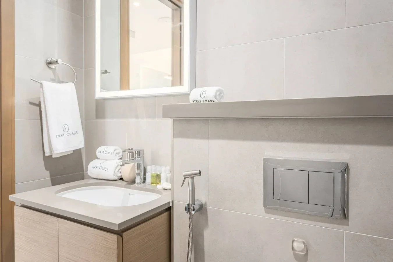 Un baño con azulejos, lavabo con mueble, espejo de pared y ducha de mano.