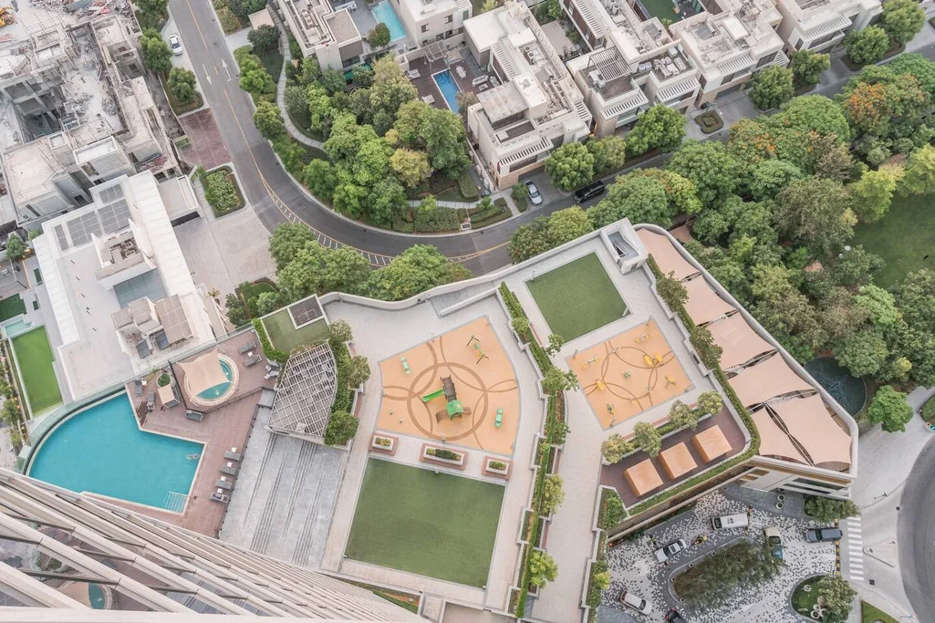 Vista aérea de una zona recreativa en una azotea con canchas, piscina y edificios alrededor.