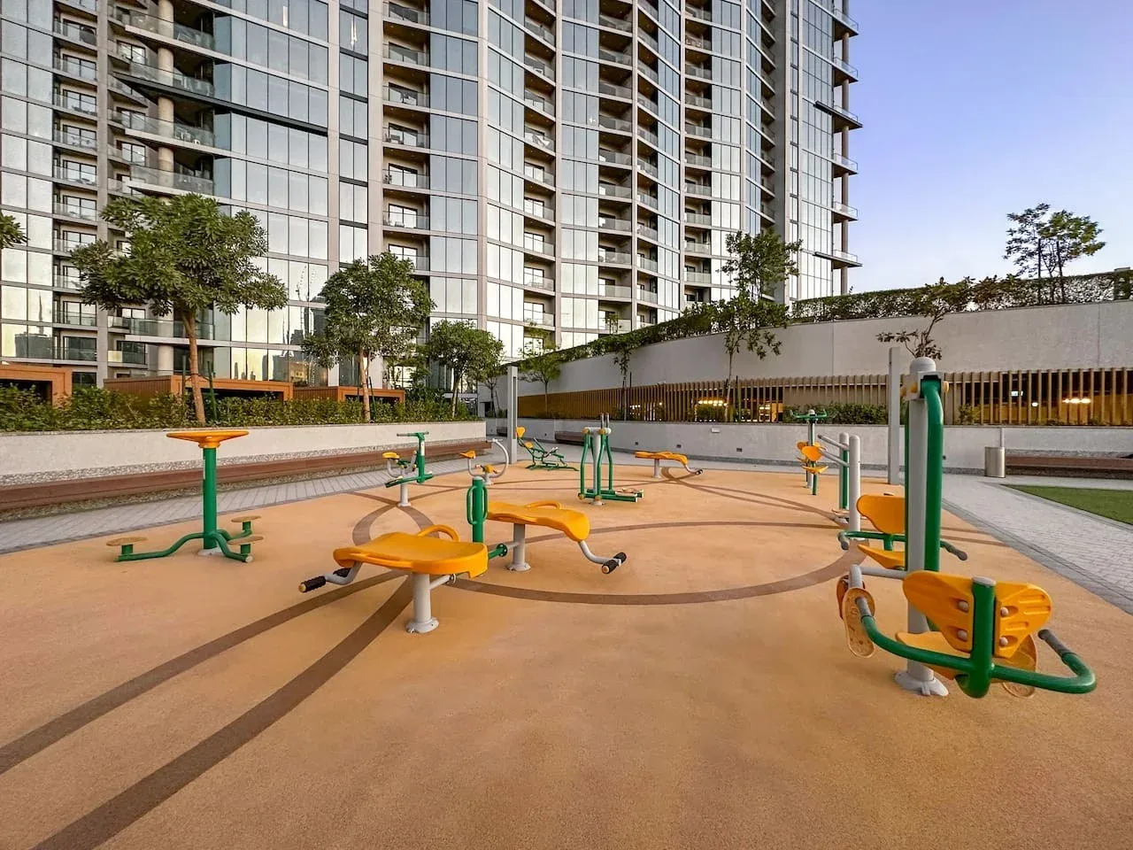 Zona de ejercicio al aire libre con equipos frente a un edificio alto.