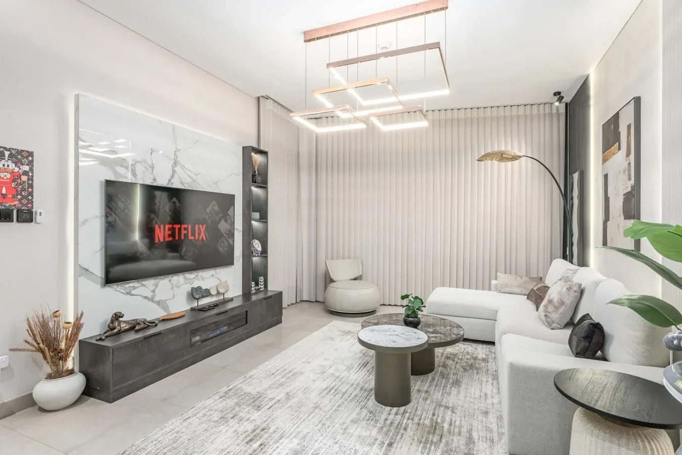 Una sala luminosa con asientos blancos, un televisor y una mesa de centro.