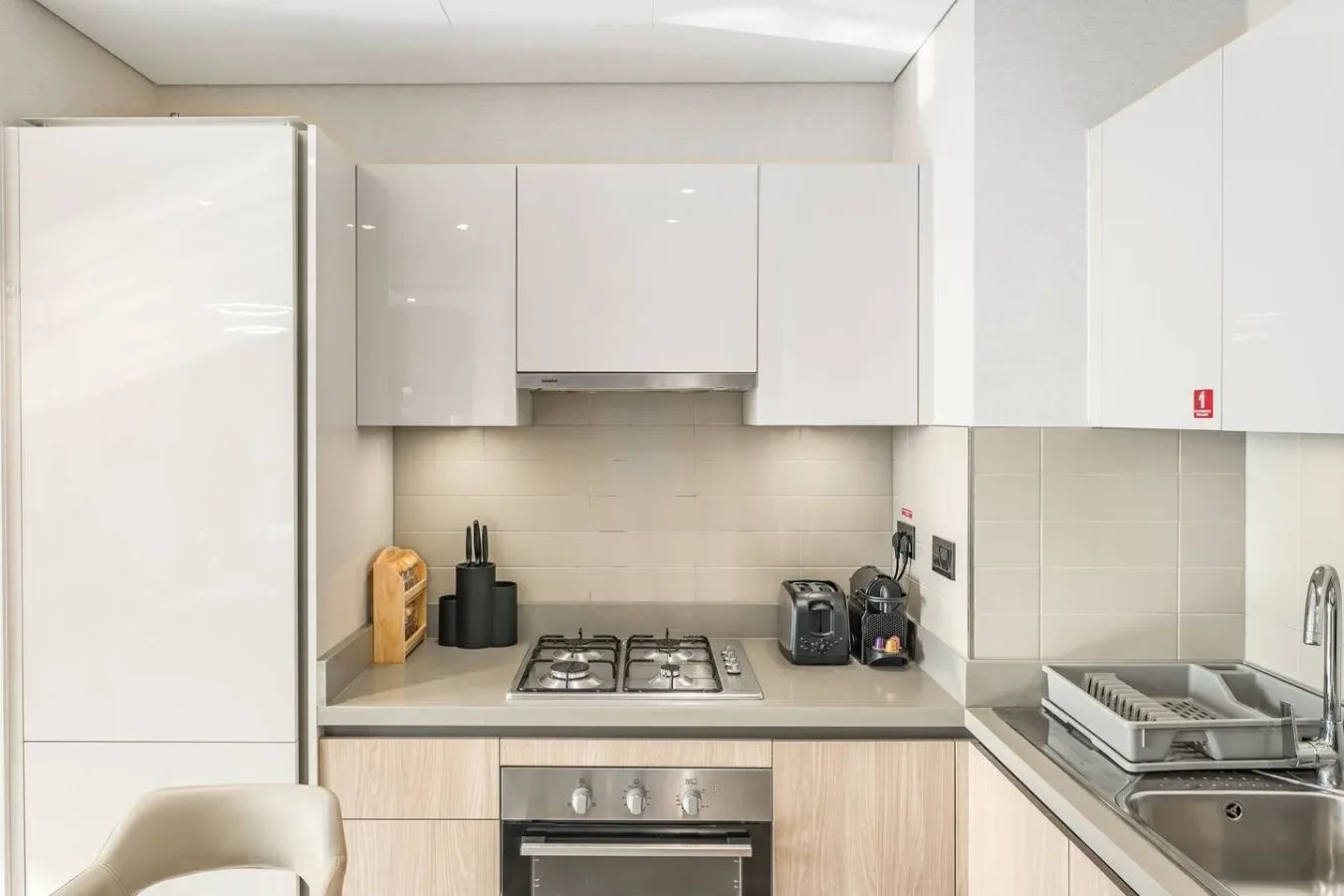 Una cocina moderna y luminosa con gabinetes blancos y una zona de cocción en la encimera.