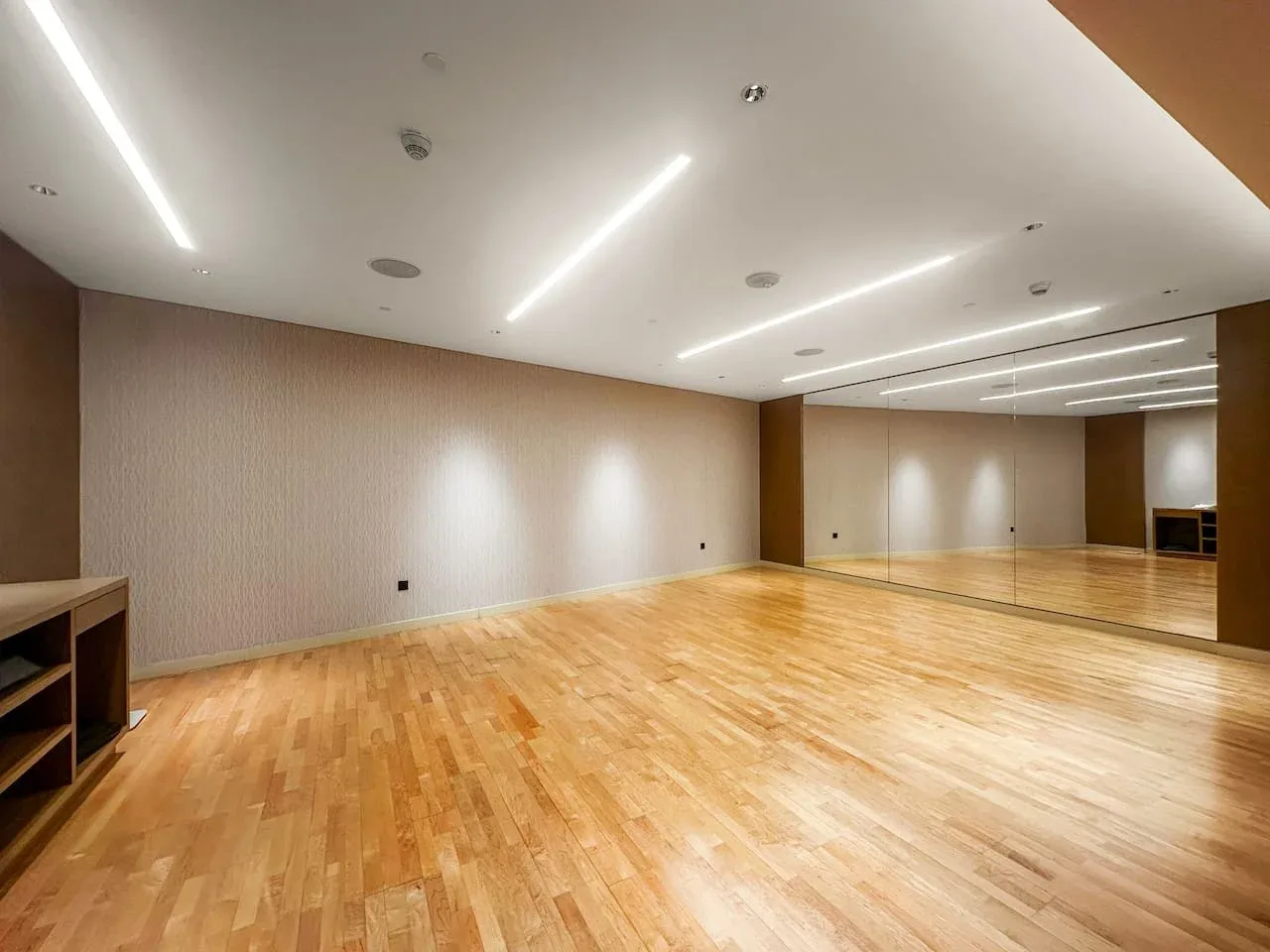 Un estudio de baile abierto con piso de madera pulida y una pared de espejos.