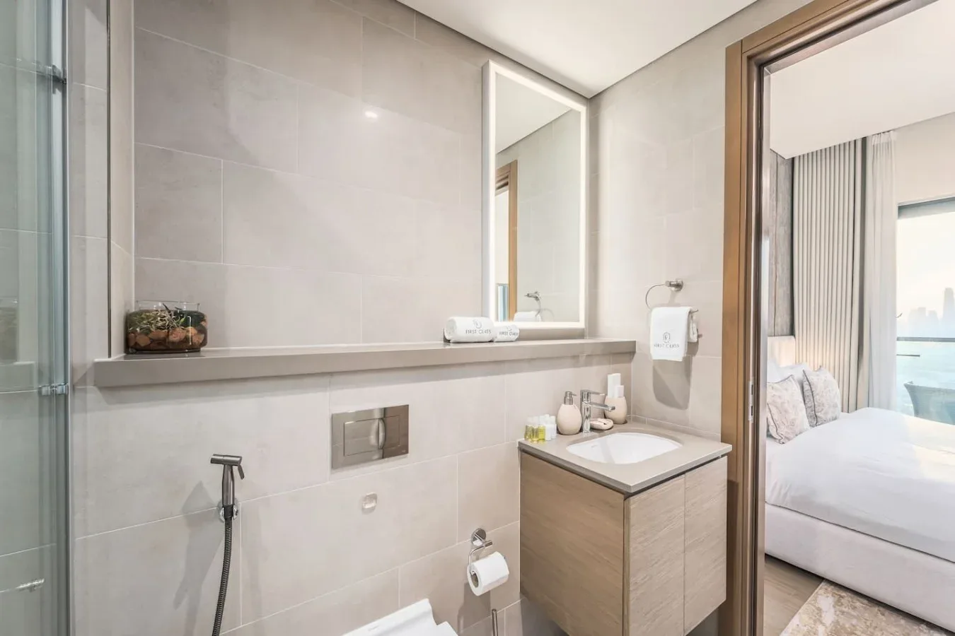 Un baño alicatado con lavabo y espejo junto a una ducha de vidrio.