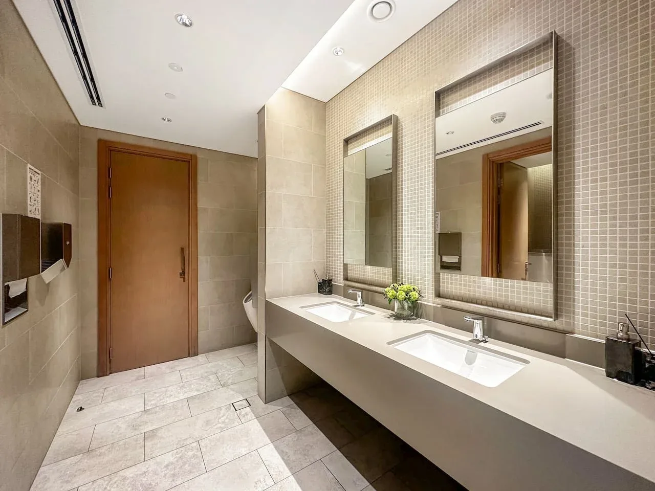 Un baño alicatado cuenta con un largo lavabo con dos lavamanos y espejos grandes.