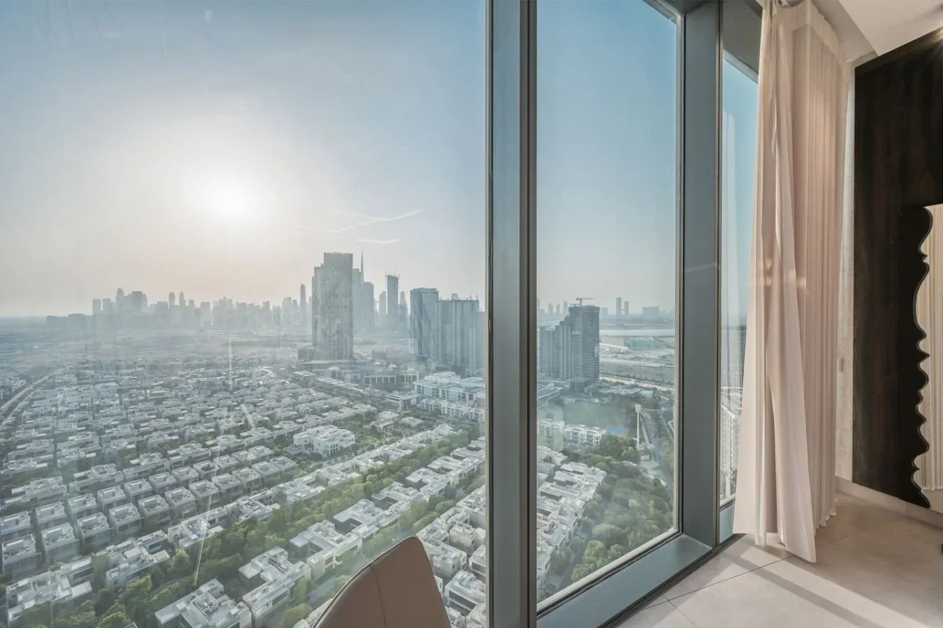 Una ventana de piso a techo ofrece vistas del horizonte urbano y filas de edificios.