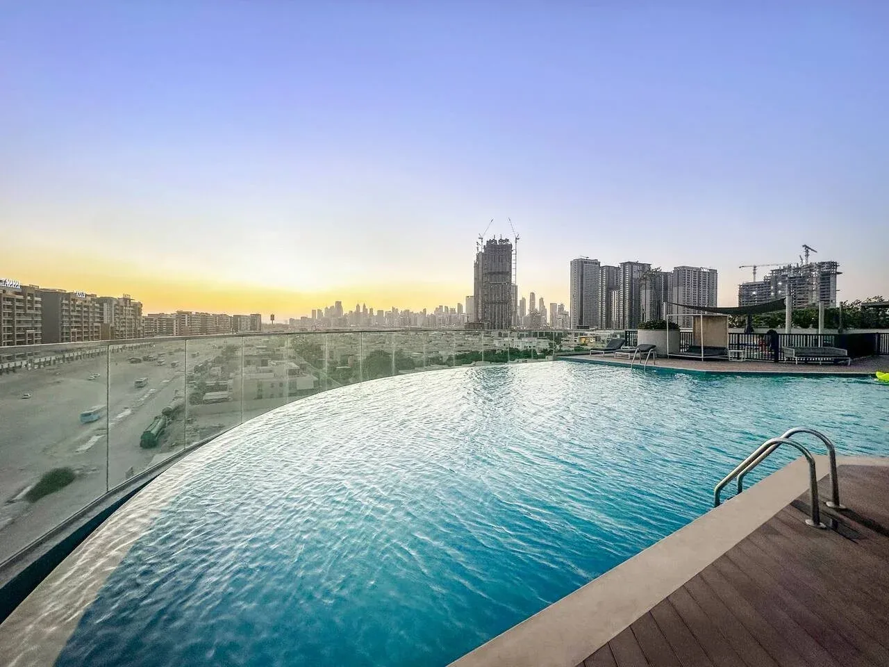 Una piscina en la azotea mira hacia edificios altos al atardecer.