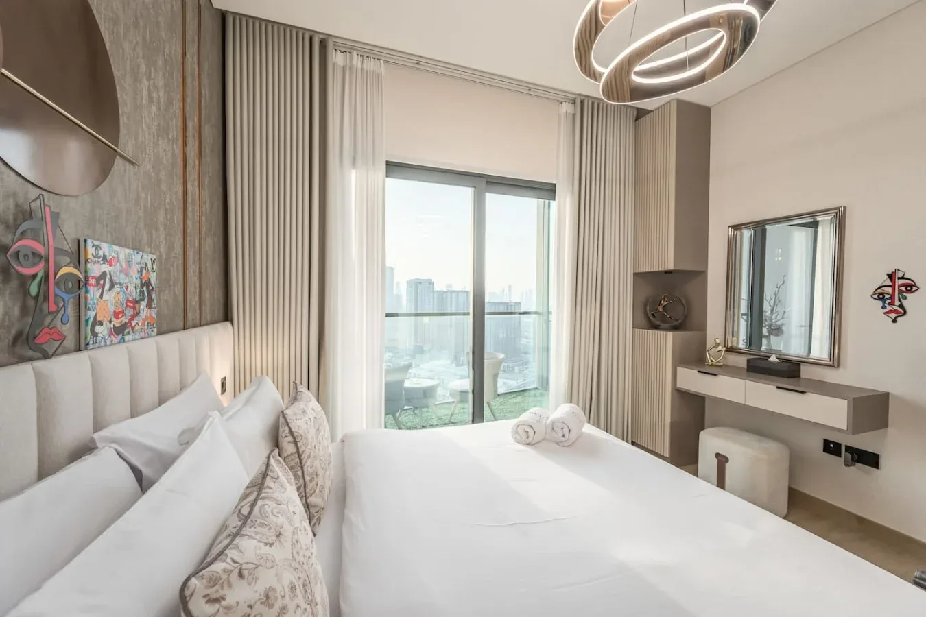 Un dormitorio luminoso con una cama grande y puertas corredizas de vidrio con vistas a la ciudad.