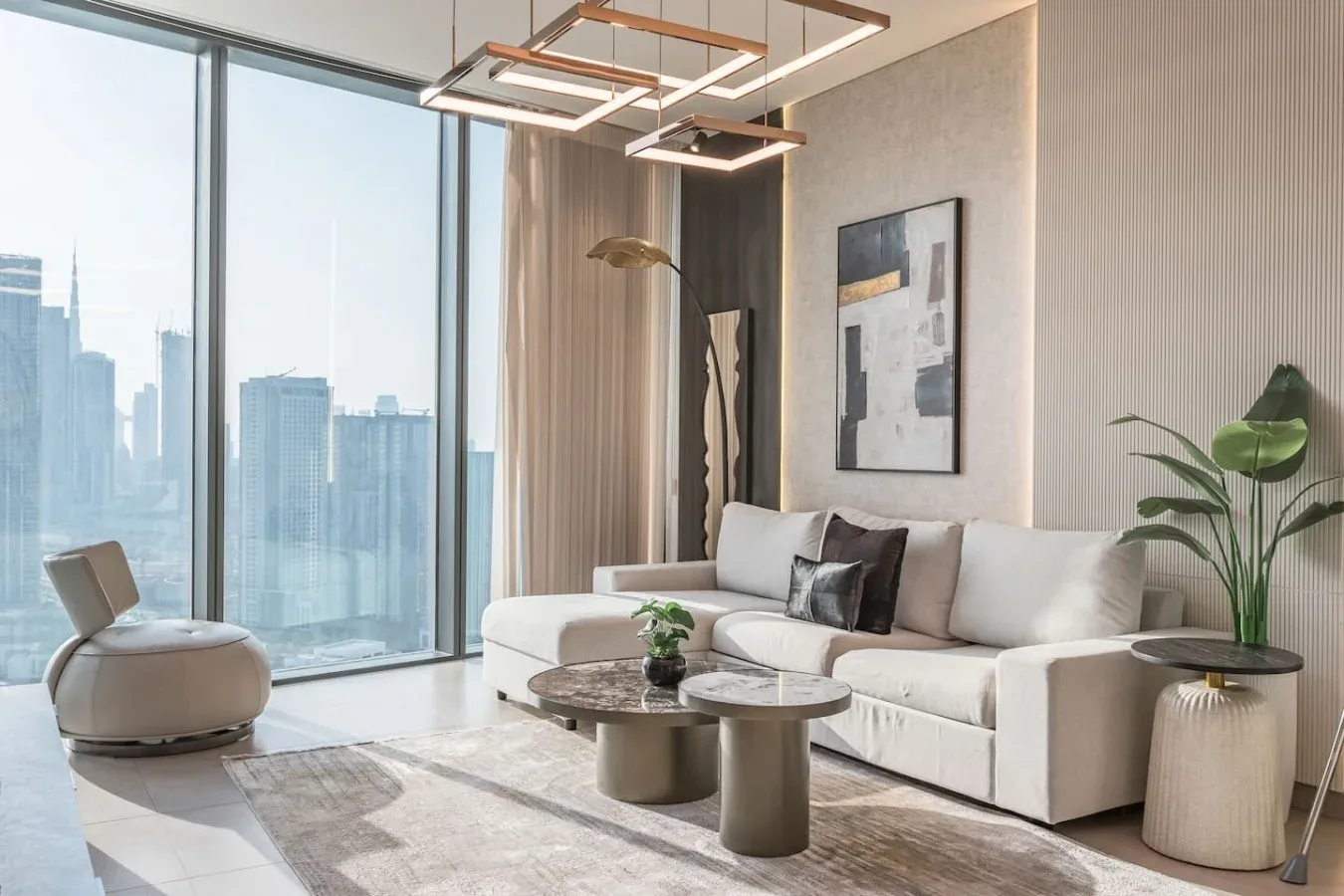Una sala de estar luminosa y moderna, con un sofá seccional blanco y grandes ventanas.