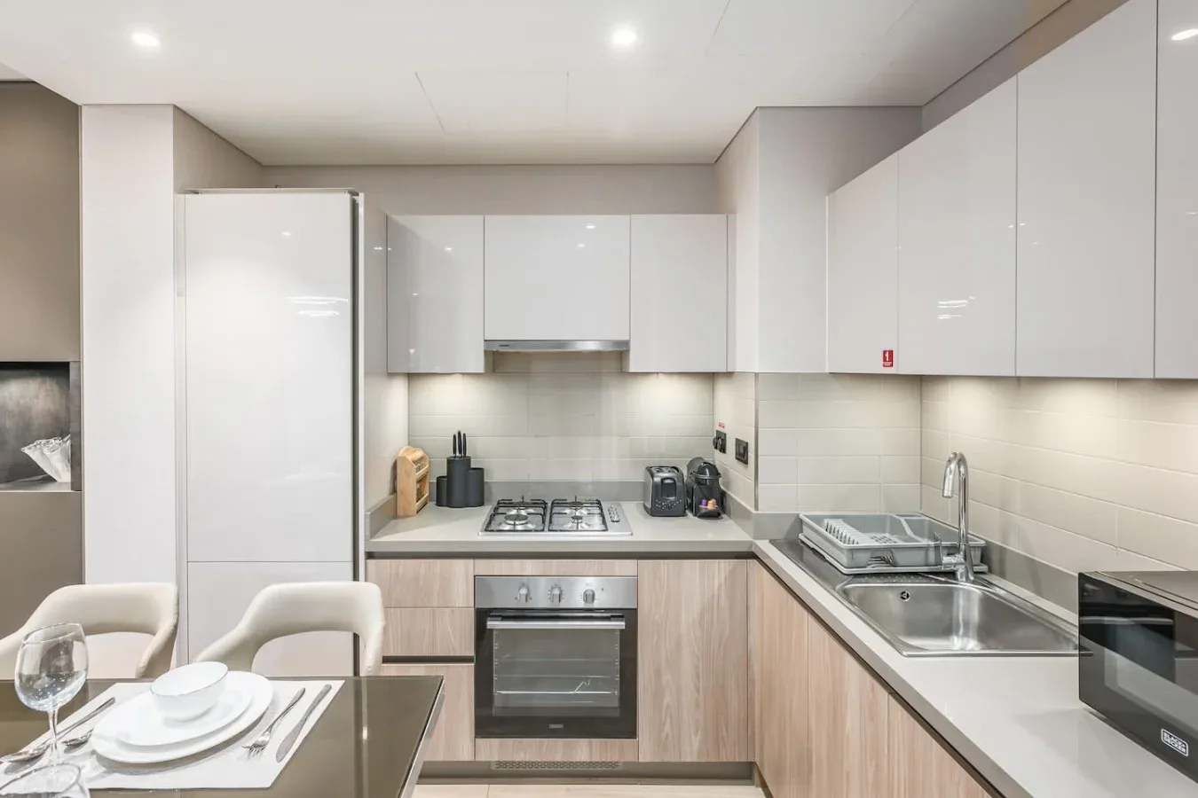 Una cocina moderna con gabinetes blancos, una placa de cocina y un fregadero.