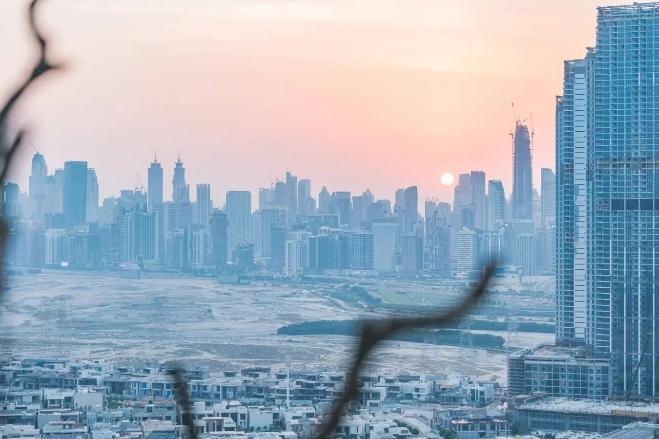 El perfil urbano al atardecer se eleva sobre una extensa zona de edificios bajos.