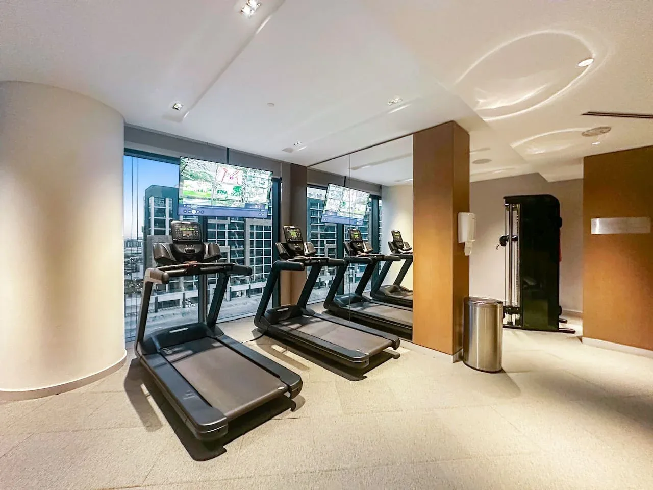 Una sala de ejercicio con cintas de correr frente a grandes ventanas.
