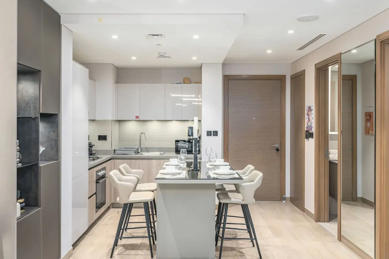 Cocina y comedor modernos con una isla y asientos de tonos claros.